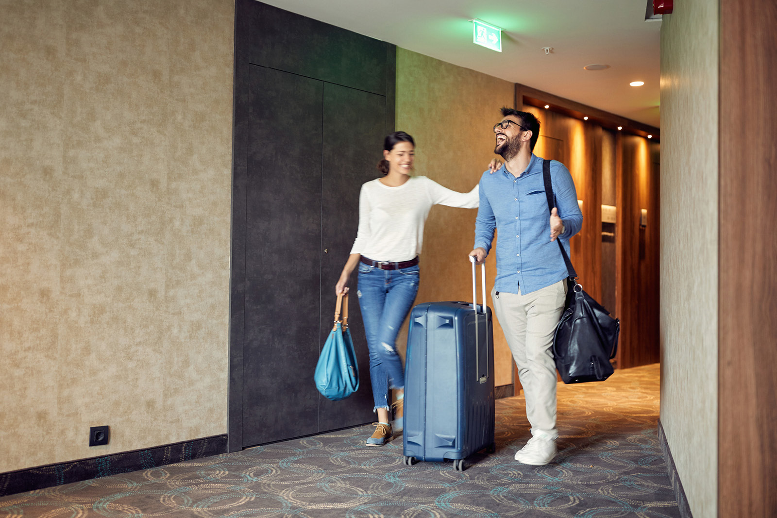 Couple holding their luggage arriving at a hotel